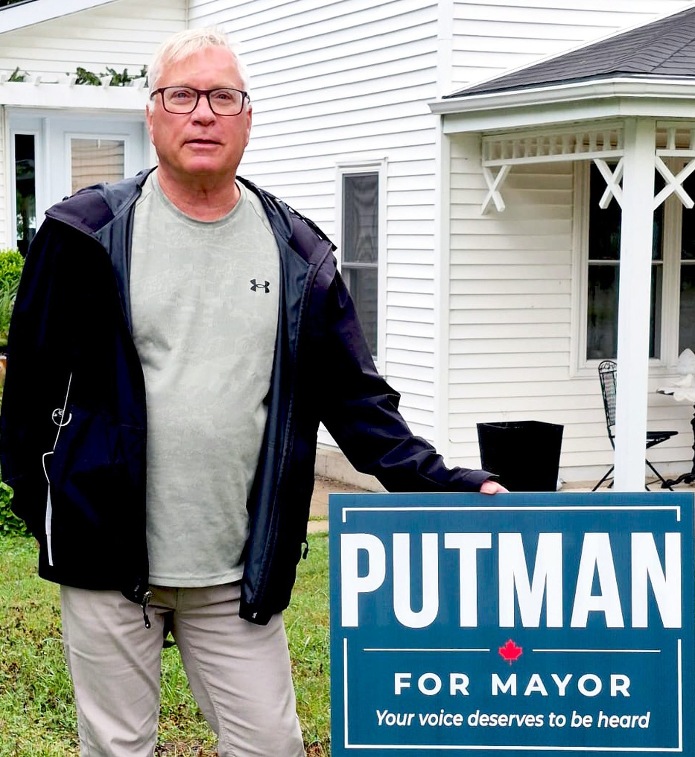 Brian Putman standing beside a Putman for Mayor lawn sign in front of a home in Southampton.